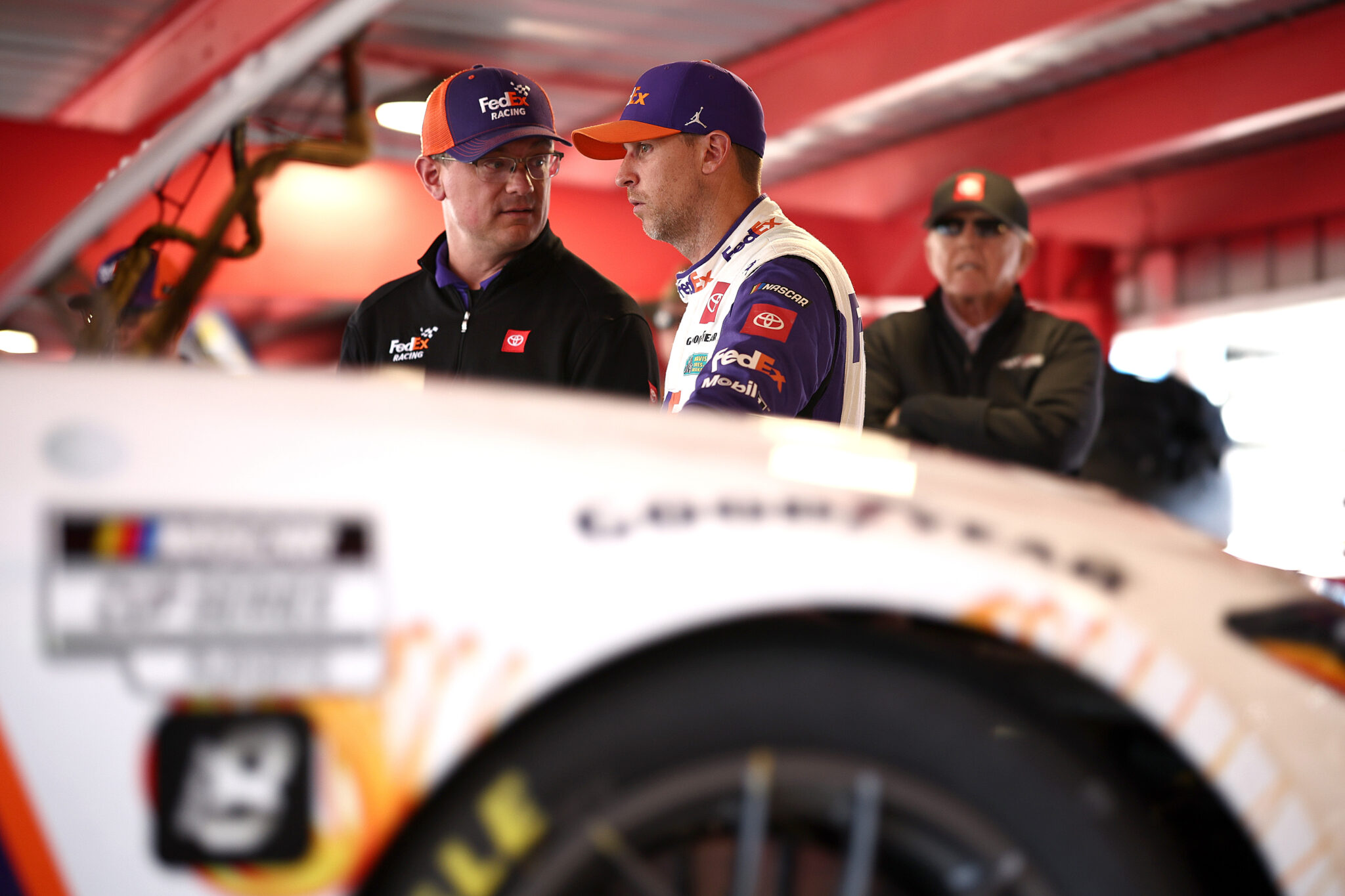 MARTINSVILLE, VIRGINIA - NOVEMBER 02: Crew chief Christopher Gabehart and Denny Hamlin, driver of the #11 FedEx One Rate Toyota, talk as JGR team owner and NASCAR Hall of Famer, Joe Gibbs looks on in the garage area after an on-track incident during practice for the NASCAR Cup Series Xfinity 500 at Martinsville Speedway on November 02, 2024 in Martinsville, Virginia. (Photo by Jared C. Tilton/Getty Images)