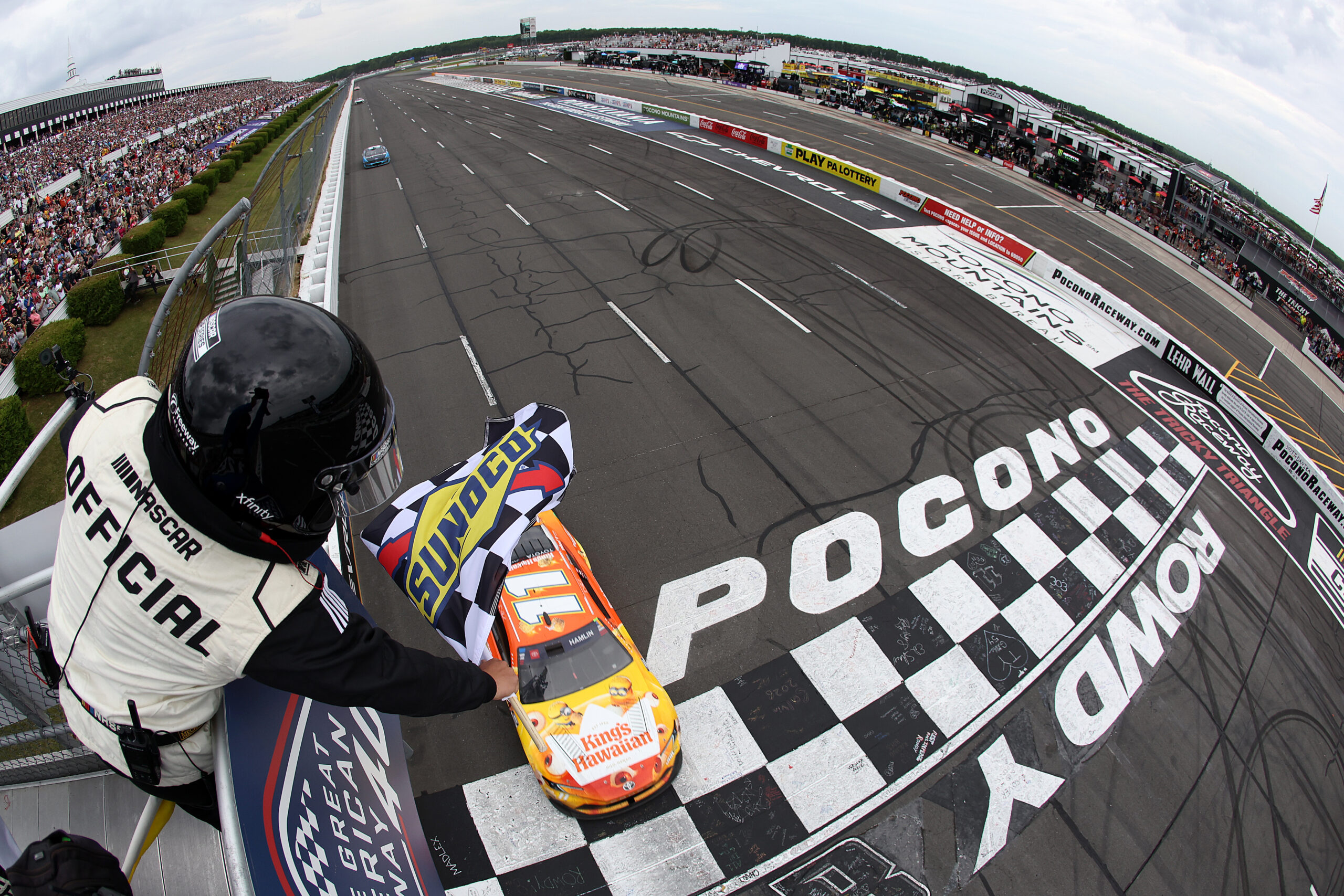 LONG POND, PENNSYLVANIA - JUNE 14: Denny Hamlin, driver of the #11 King's Hawaiian Shake 'Em Bites Toyota, takes the checkered flag to win the NASCAR Cup Series Great American Getaway 400 presented by VISITPA at Pocono Raceway on June 14, 2026 in Long Pond, Pennsylvania.